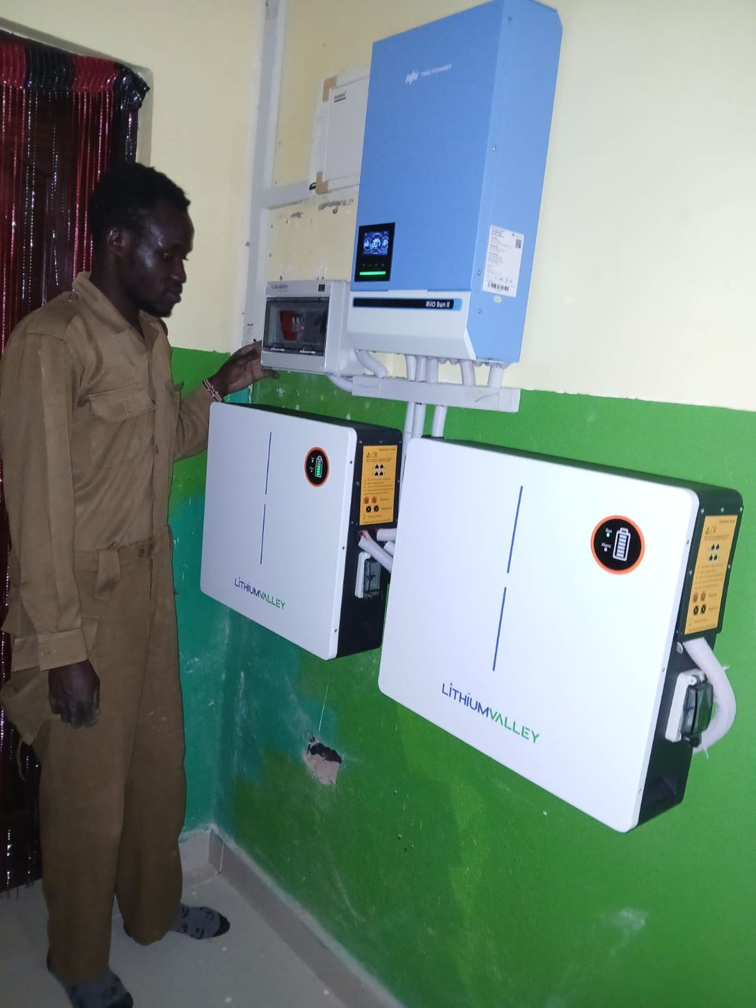 Technician inspecting inverter and lithium battery installation indoors