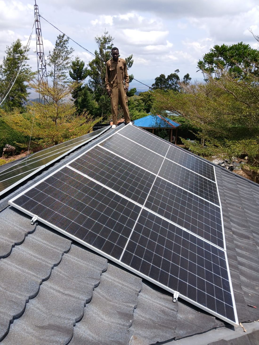 Technician on a tiled roof beside newly installed solar panels